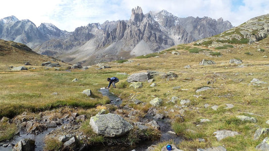Water filter bottle in use with high river in the french alps